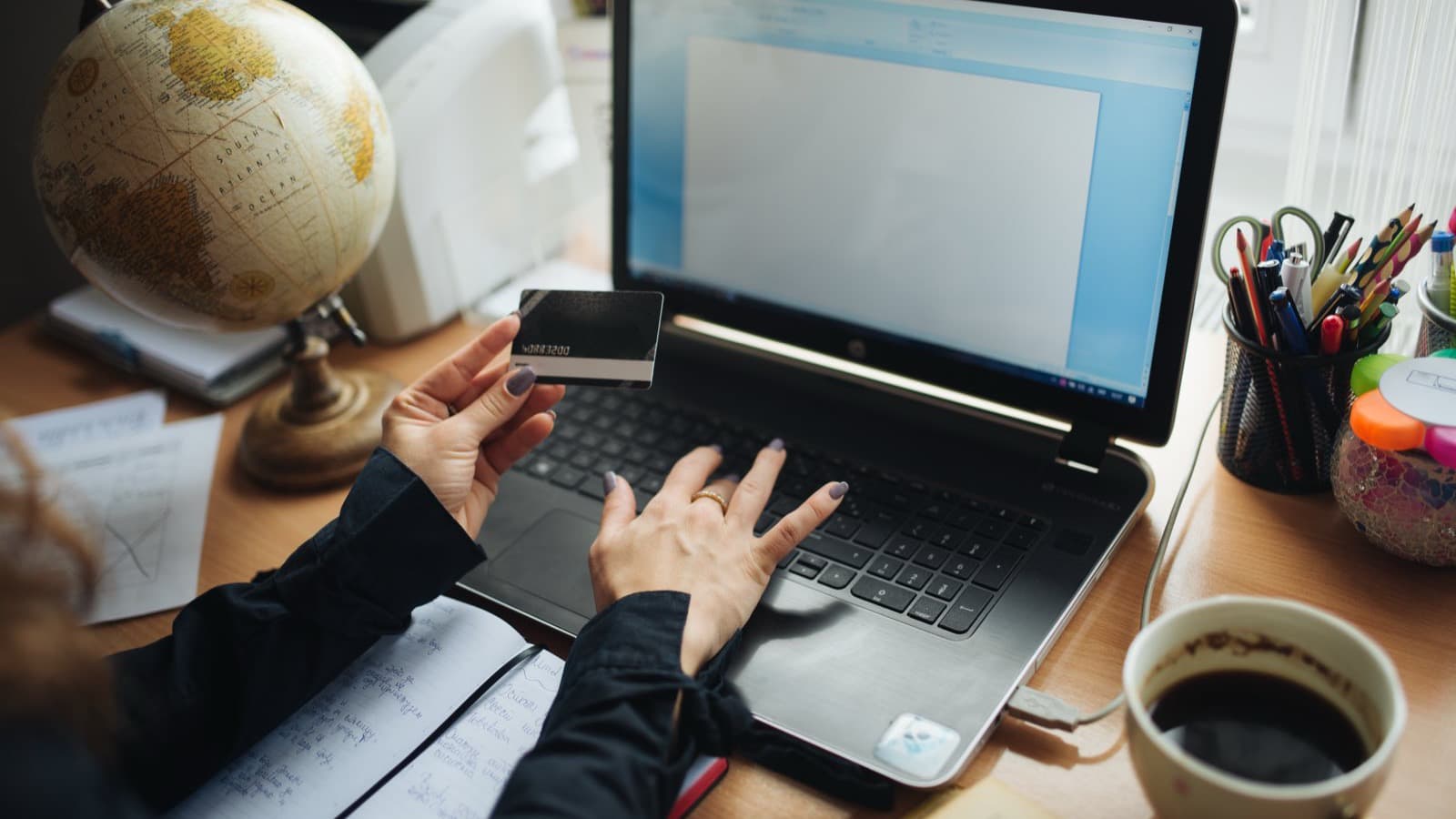 Person reviewing a payment card while working on a laptop.