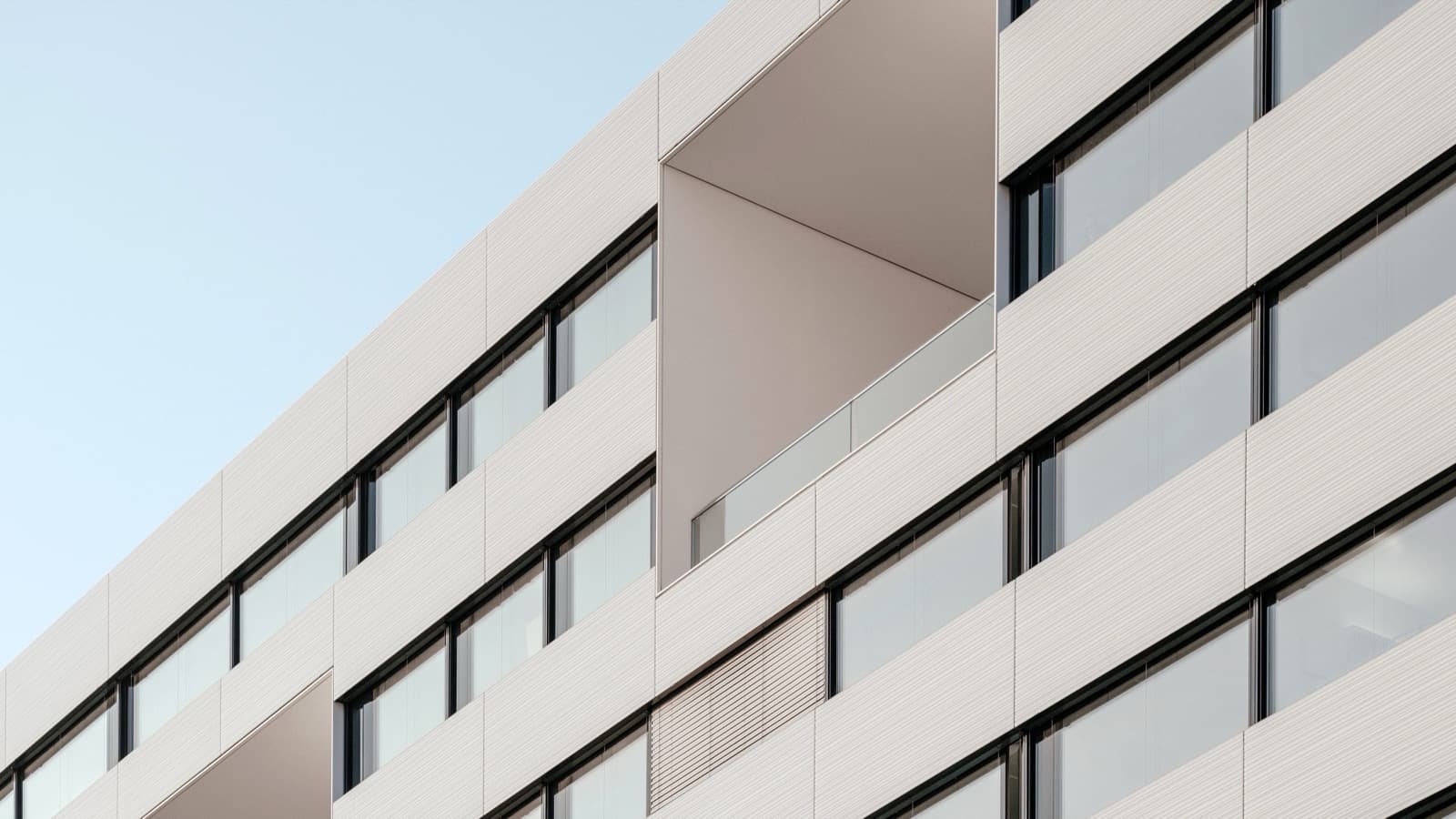 Modern residential building facade with rows of windows and balconies.